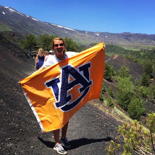 Auburn student holding Auburn flag on mountain side